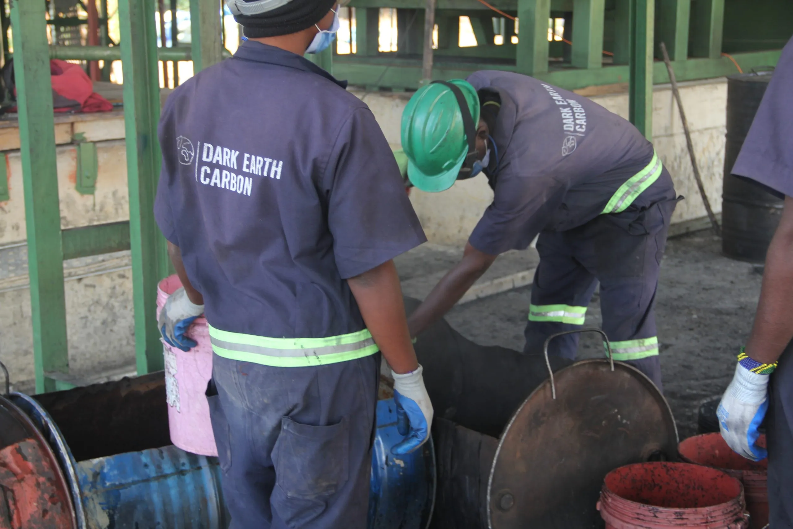 Two operators in Dark Earth Carbon overalls working at the char discharge drums