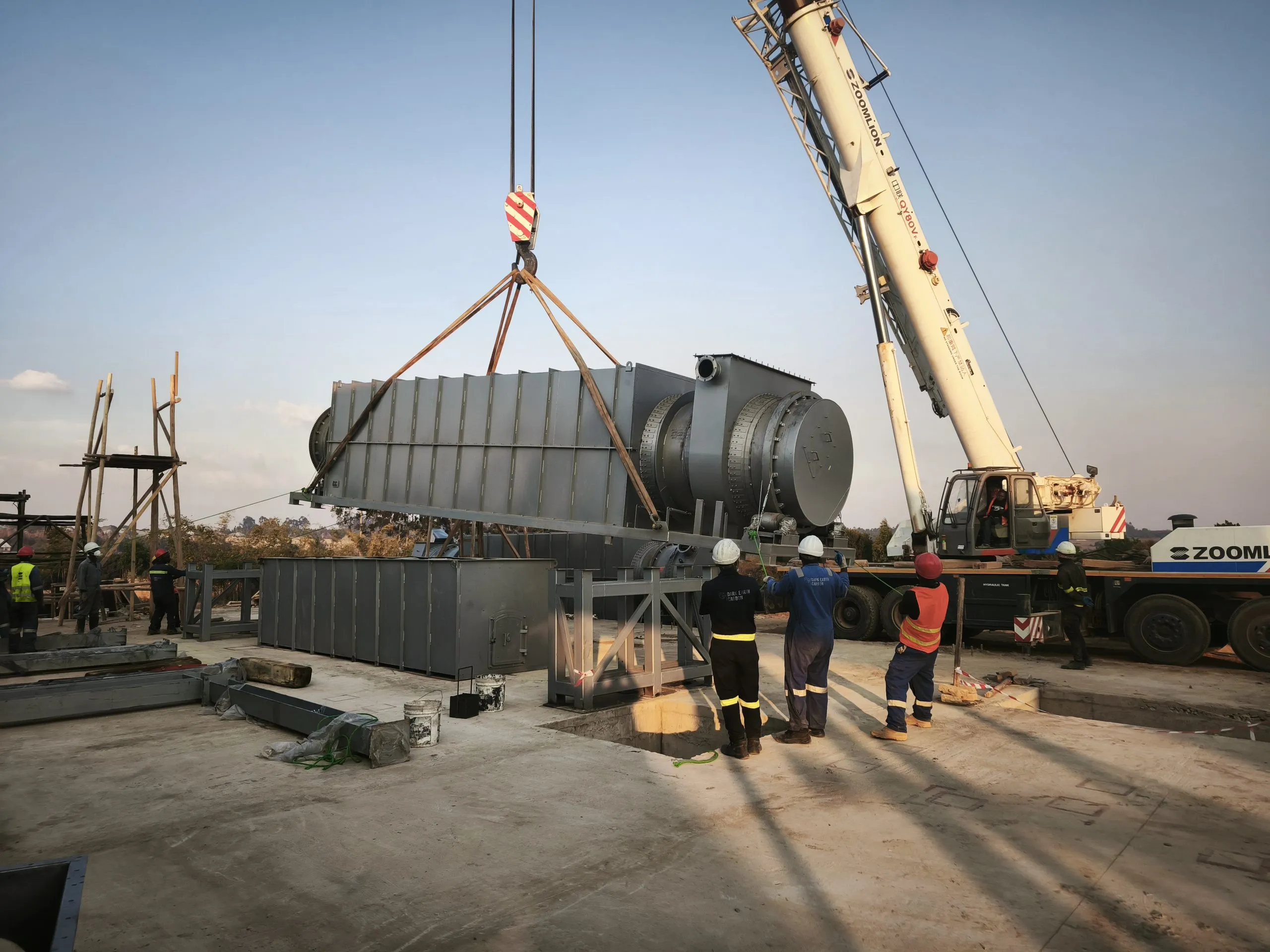 A crane lowering a pyrolysis module onto its foundation while the installation crew guides it in